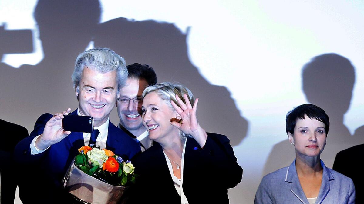 Marine le Pen, leader of France's far-right National Front, waves as Dutch populist lawmaker Geert Wilders takes a picture after their speeches Saturday at a meeting in Koblenz, Germany.