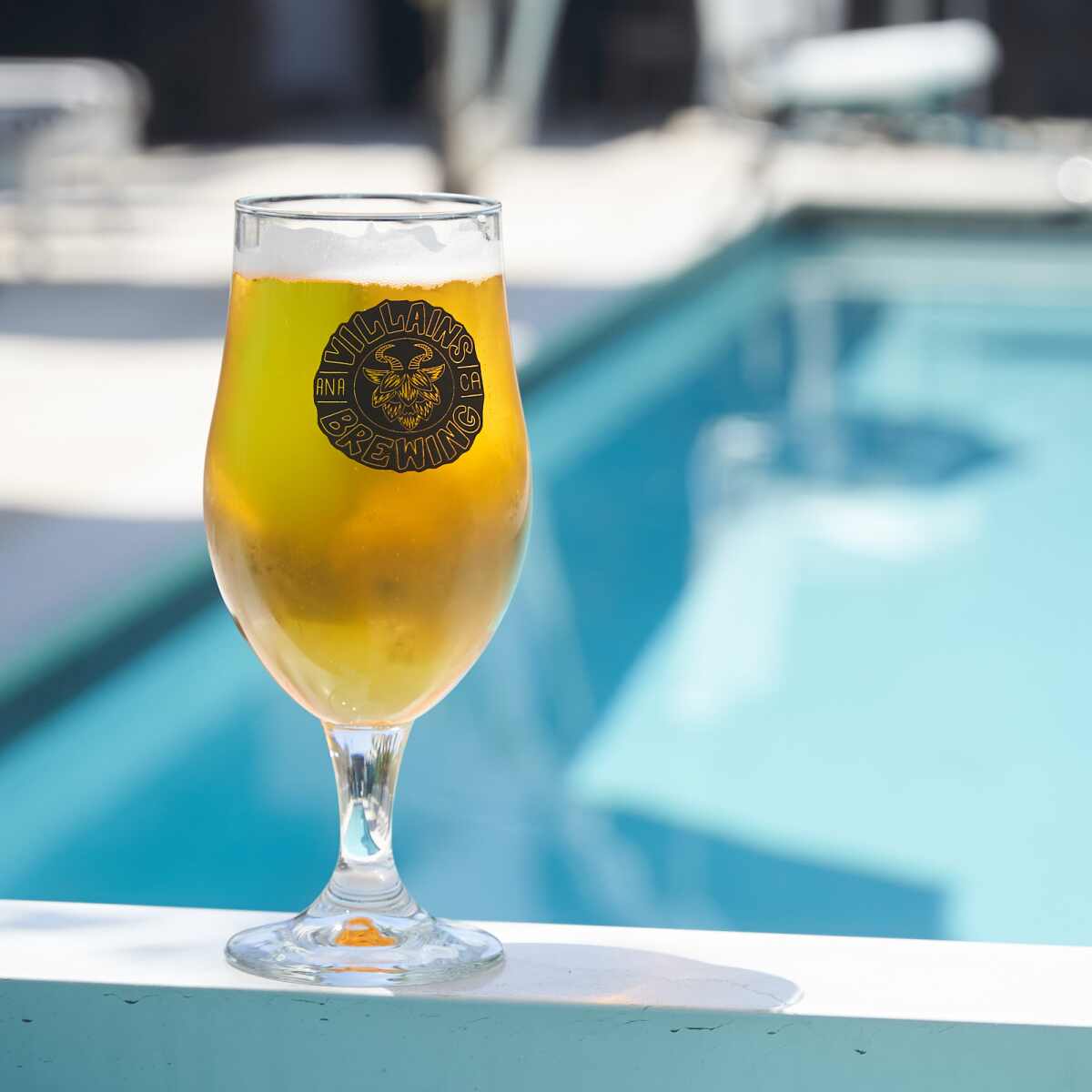 A glass of beer at Villains Brewing Co. in front of a swimming pool.