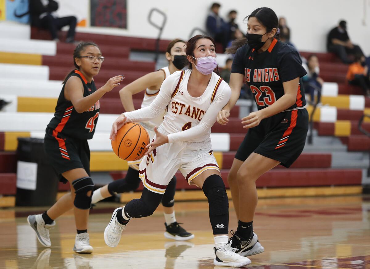 Estancia's Alexis Orellana (4) drives around Giselle Hernandez (23) of Los Amigos in December. 