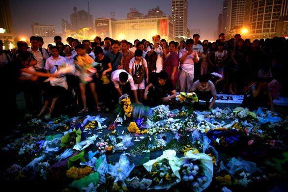 People place flowers, light candles, and chant national slogans in memory of earthquake victims at the People's Square in Chengdu, China.