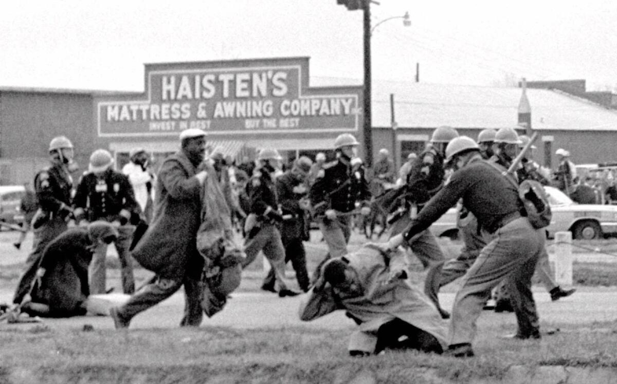 Alabama state troopers swing nightsticks to break up the "Bloody Sunday" voting march in Selma, Ala., on March 7, 1965. John Lewis, front right, of the Student Non-violent Coordinating Committee, is put on the ground by a trooper.