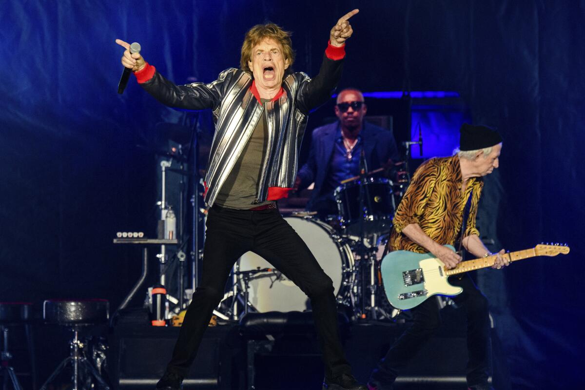 The Rolling Stones on stage with Mick Jagger in front flexing his hips.