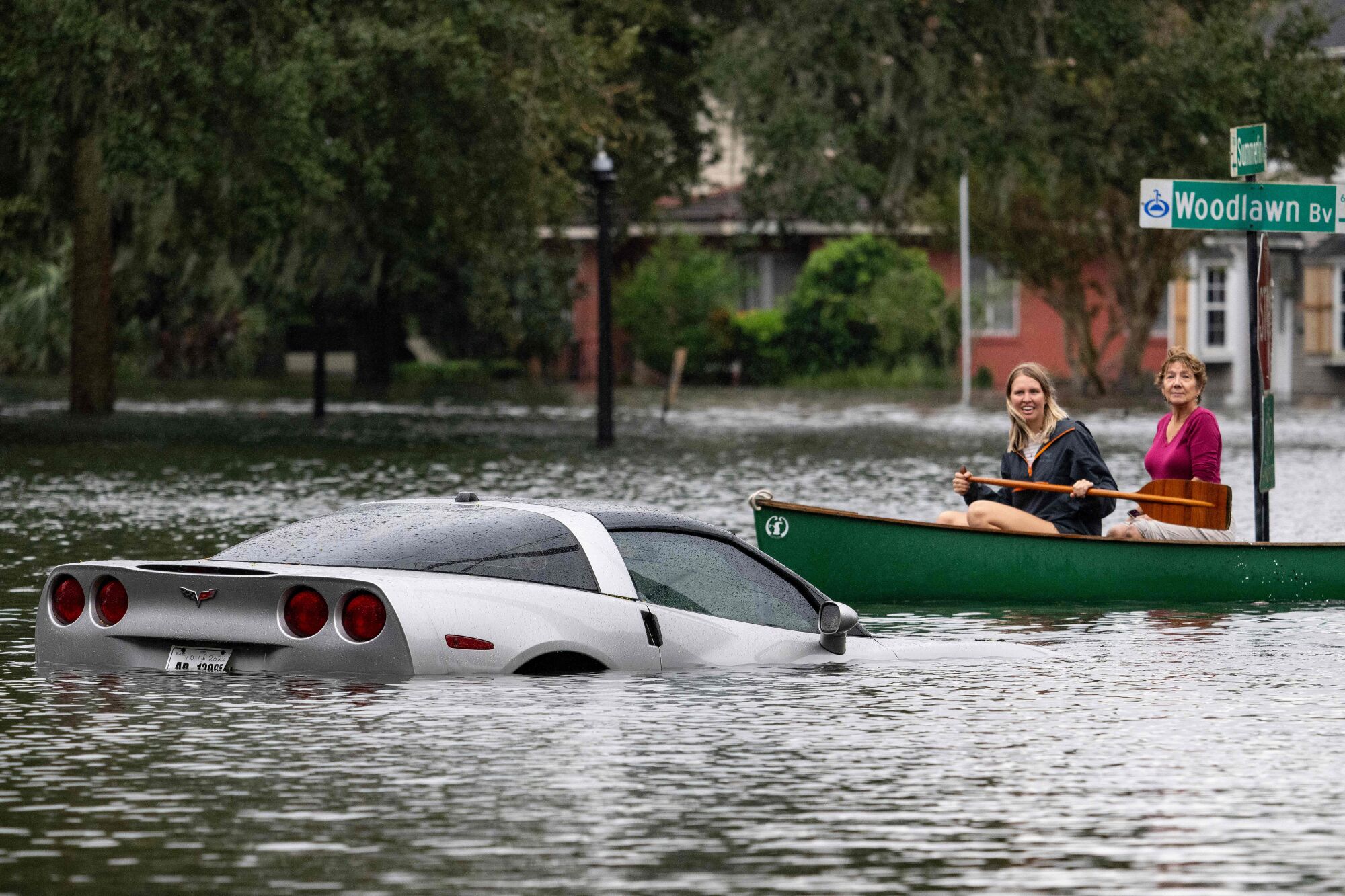 People paddle by in a canoe next to a submerged Corvette in the aftermath of Hurricane Ian in Orlando, Fla.