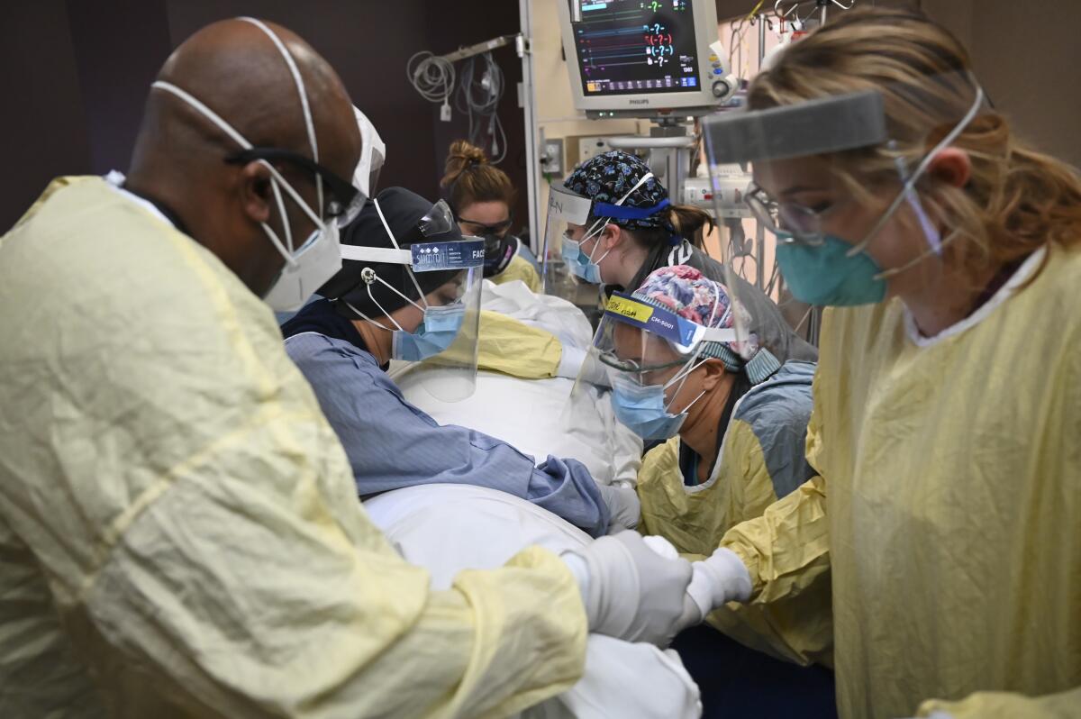 Nurses and respiratory therapists work on a COVID-19 patient.
