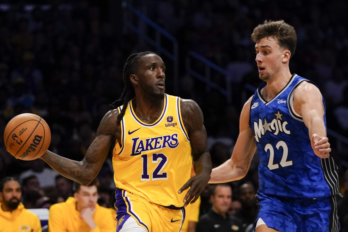 Lakers forward Taurean Prince, left, looks to pass the ball while driving against Magic forward Franz Wagner.