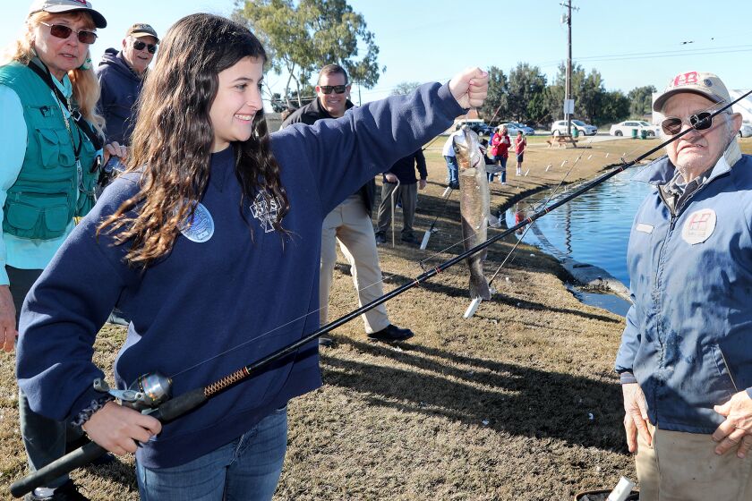 Kylie Hunnicutt, 11, a fifth-grader at St. Bonaventure Catholic School, holds up a trout fish she caught during the OFish with the ForceO event on Friday morning at Carr Park in Huntington Beach. (Kevin Chang / Daily Pilot)