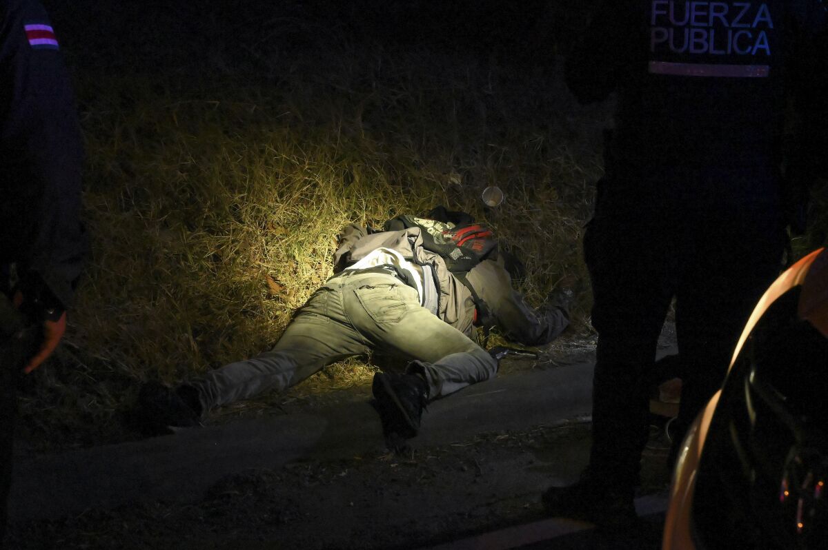 FILE - The body of a man is illuminated by police flashlights as investigators work a crime scene where an alleged thief and a female passenger died in a shootout during a robbery on a bus in San Jose, Costa Rica, Feb. 6, 2023. According to the authorities, the Central American nation has reached its highest murder rate since the Organization of Judicial Investigation office has kept records. (AP Photo/Carlos Gonzalez, File)