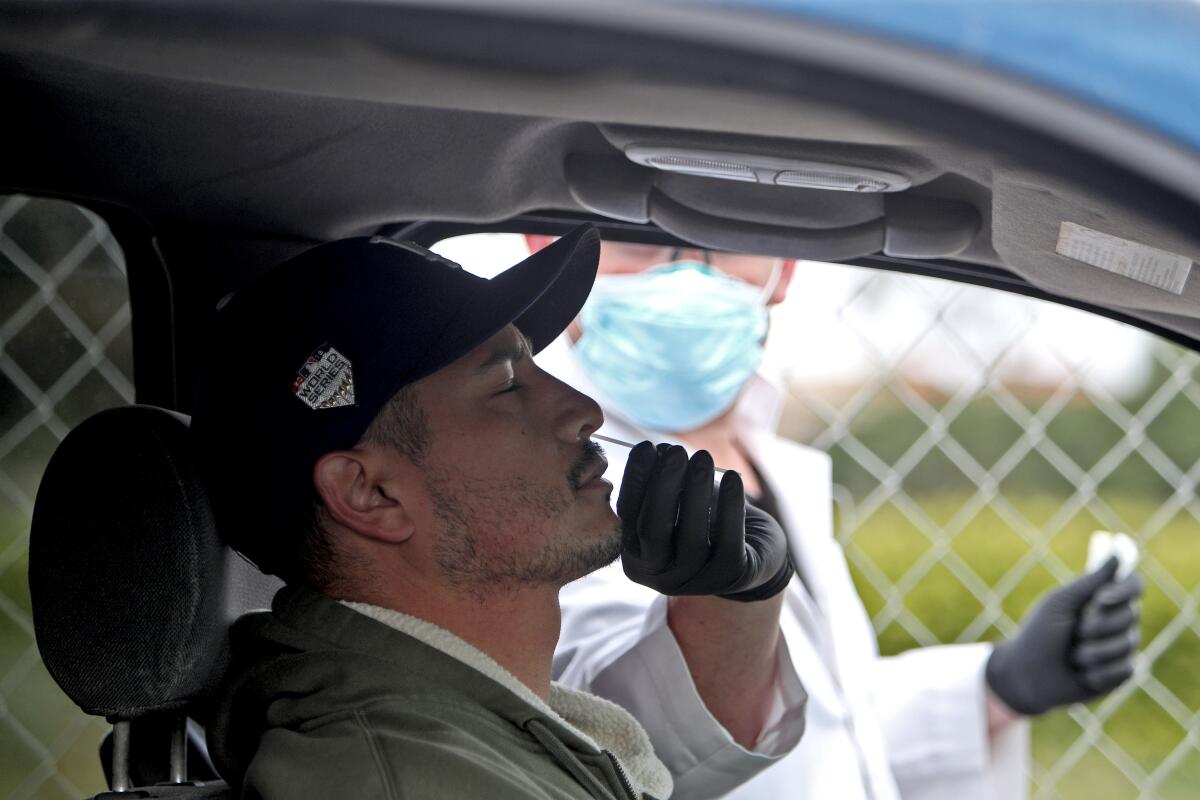 Marcos Padilla of Anaheim gets a drive-up coronavirus test from Dr. Matthew Abinante outside Abinante's office in Huntington Beach on Thursday.