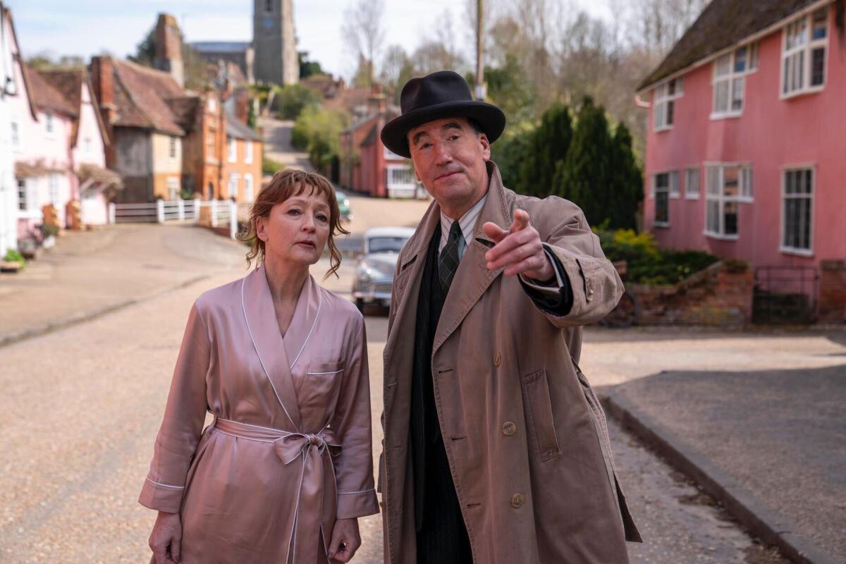 A woman in a nightgown and a man in a trenchcoat on a quiet street