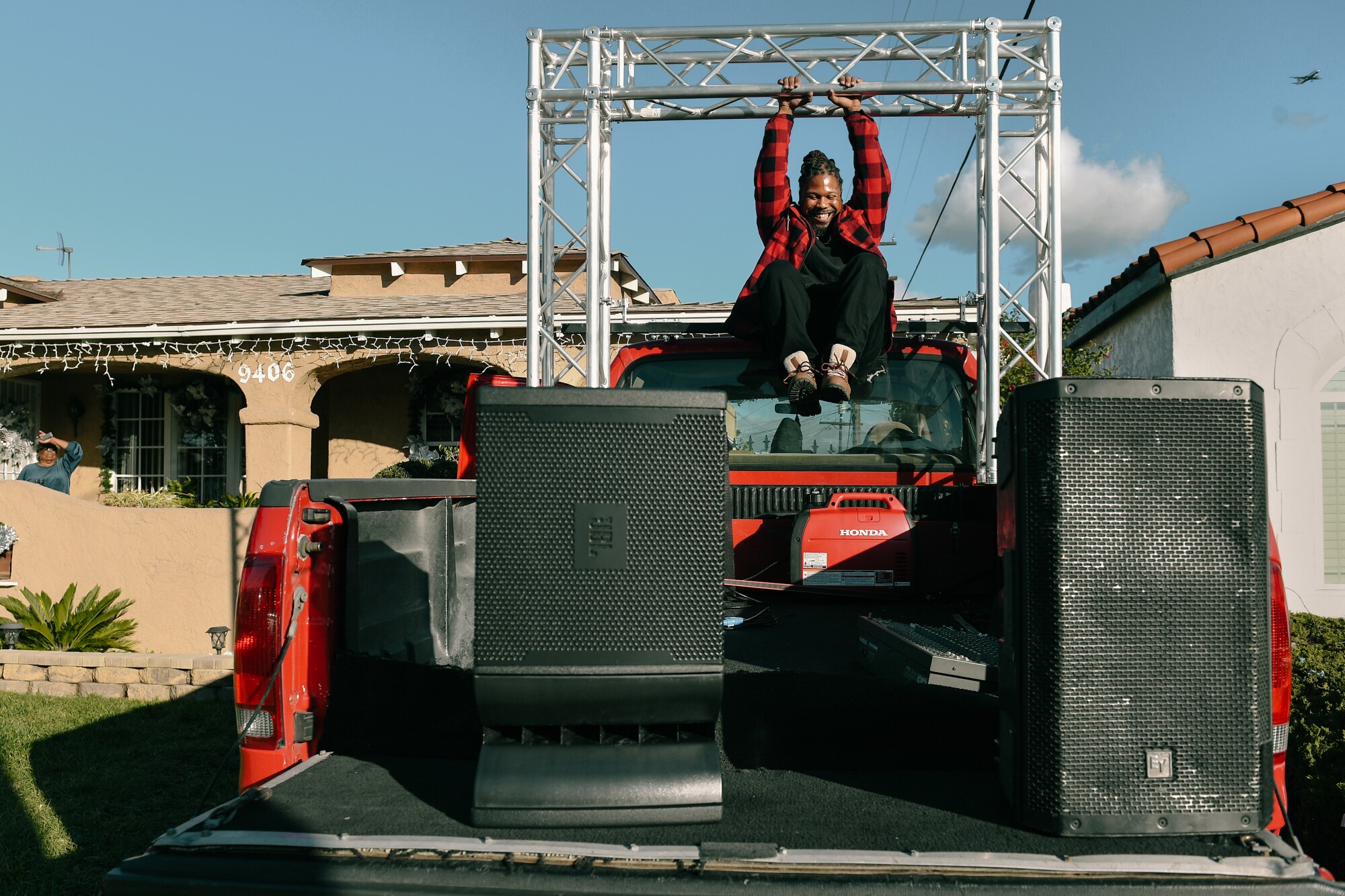 A man hangs from a support bar on a pickup truck