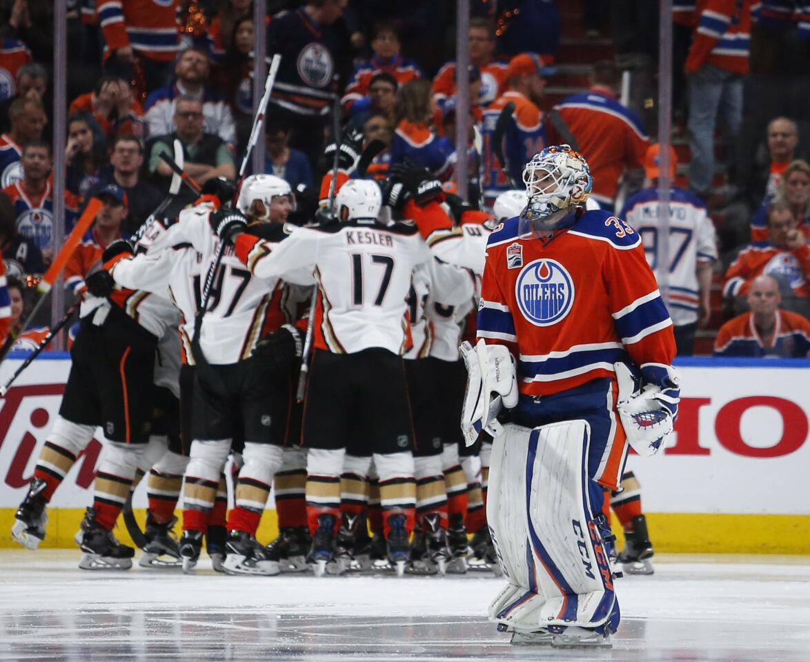 Ducks players celebrate their overtime victory as Oilers goalie Cam Talbot skates off the ice.