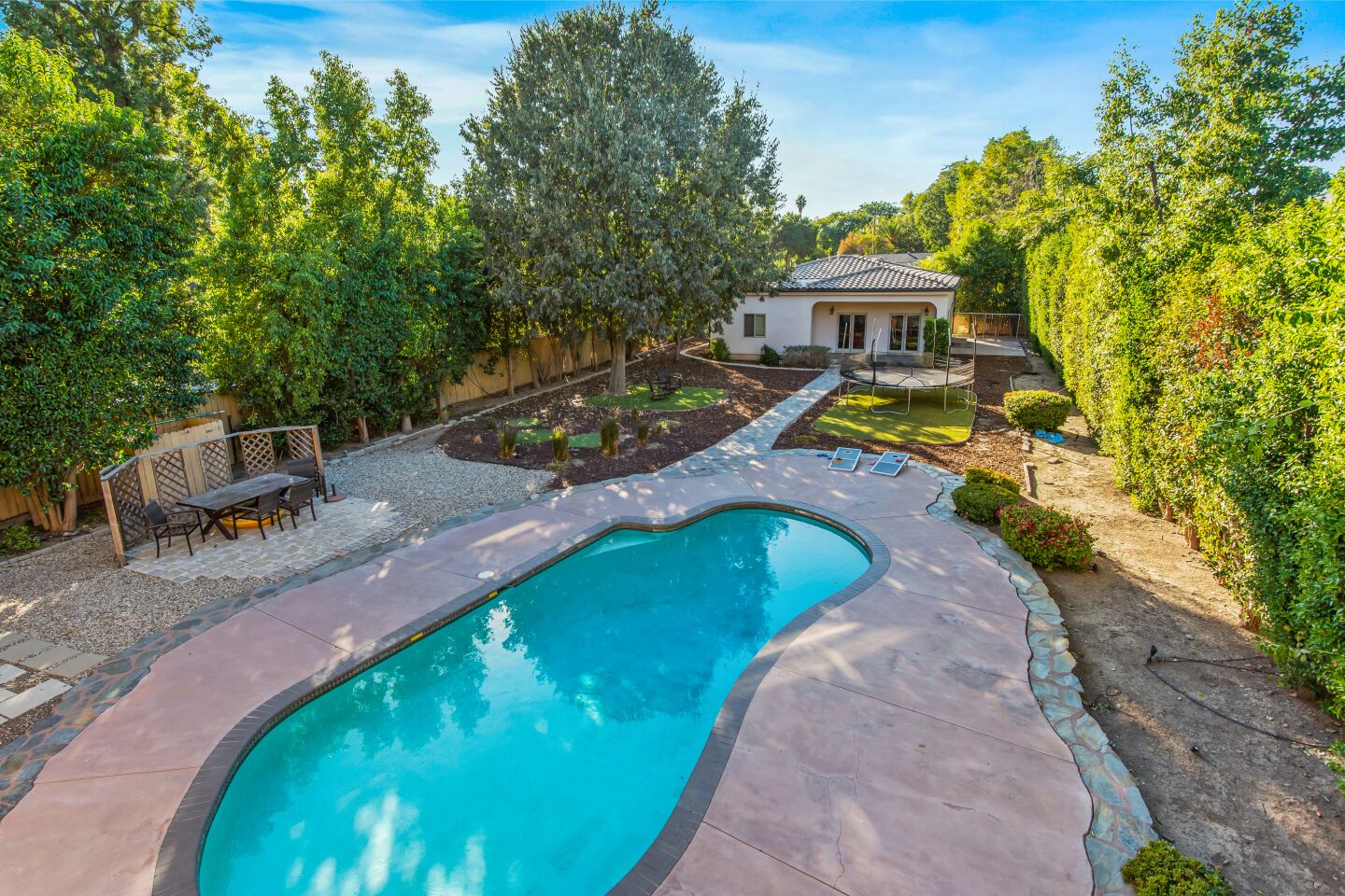 The swimming pool has a nearby guesthouse and trampoline.