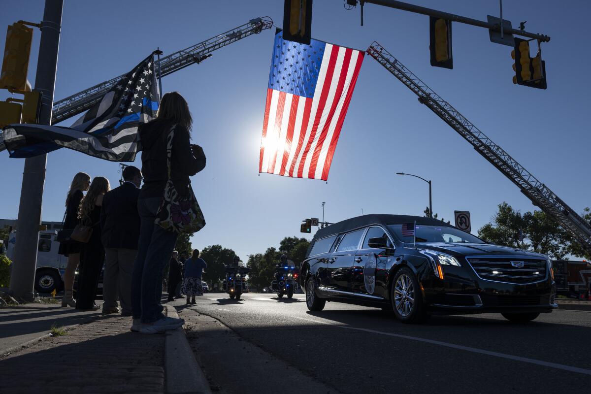Mourners line the road as the hearse carrying fallen Arvada Police officer Dillon Vakoff drives by on Friday, Sept. 16, 2022, at Flatirons Community Church in Lafayette, Colo. Vakoff was fatally shot while trying to break up a large family disturbance earlier in the week, in Arvada. (Timothy Hurst/The Gazette via AP)