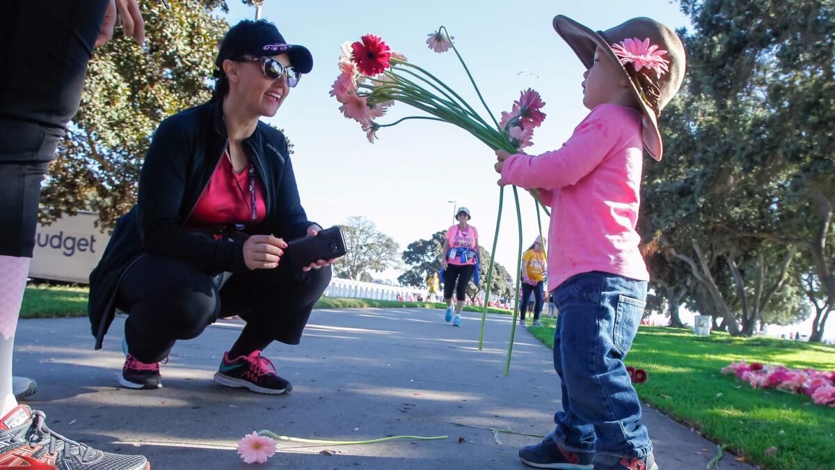 Archer Steed (right), 2, offers a Gerbera daisy to walker Toni Van Valkenburg during the Susan G. Komen 3-Day on Saturday at Bonita Cove on Mission Bay in San Diego. Dramm and Echter, a flower farm in Encinitas, donated 10,000 Gerbera stems to the walk.