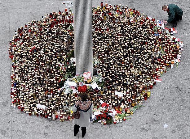 People stop at the base of a giant cross at Pilsudski Square in Warsaw where candles have been left in memory of the 96 people, including the country's president and other prominent leaders, who died in an air crash on April 10.