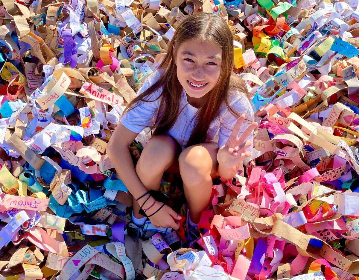 A girl holds up a peace sign while sitting among paper links