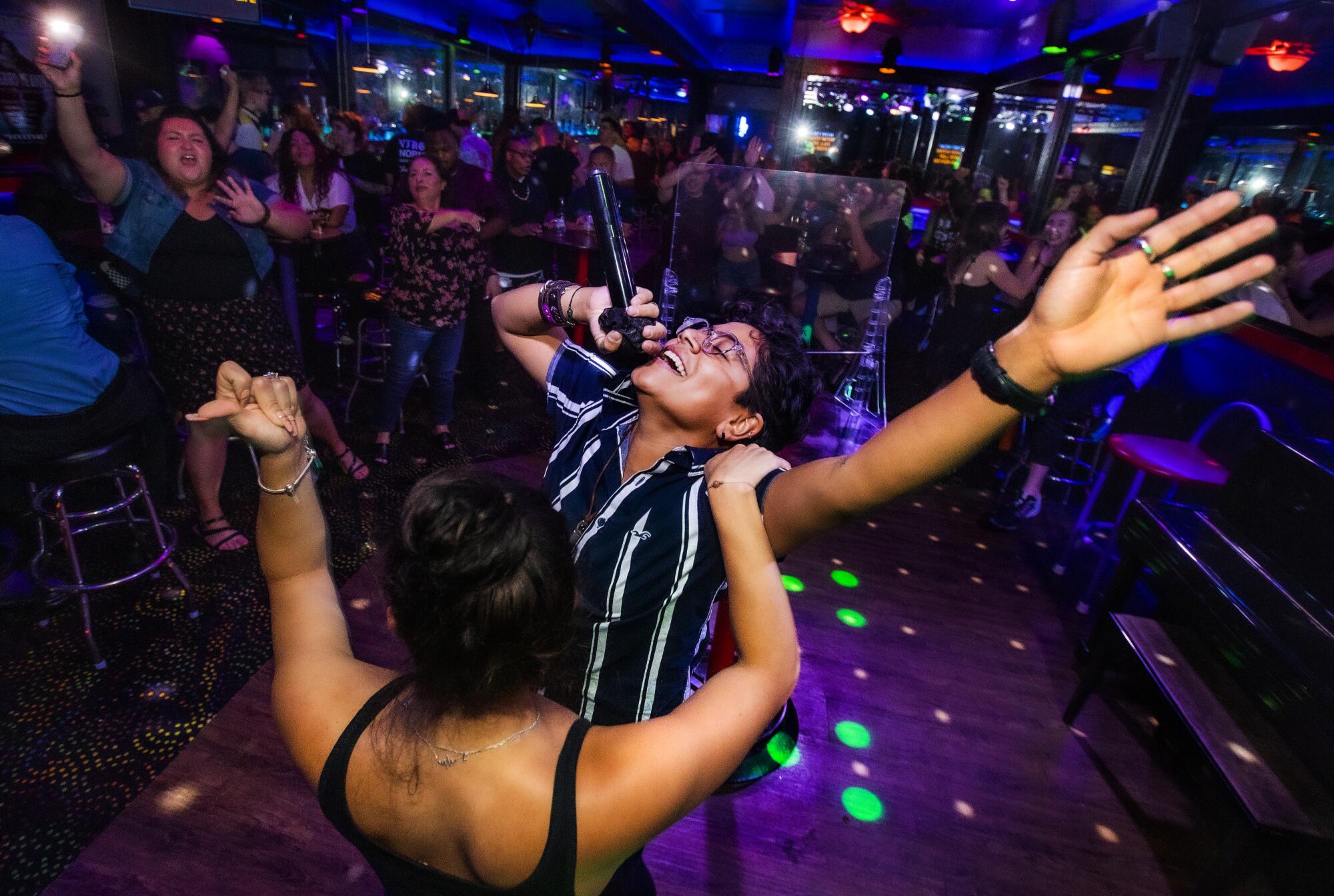 Two people perform karaoke on a colorfully lit dance floor at the Boulevard.