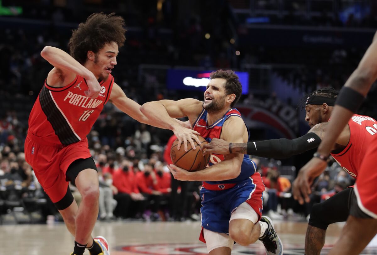 Washington Wizards' Raul Neto, center, is fouled as Portland Trail Blazers' CJ Elleby (16) and Robert Covington, right, defend during the first half of an NBA basketball game, Saturday, Jan. 15, 2022, in Washington. (AP Photo/Luis M. Alvarez)