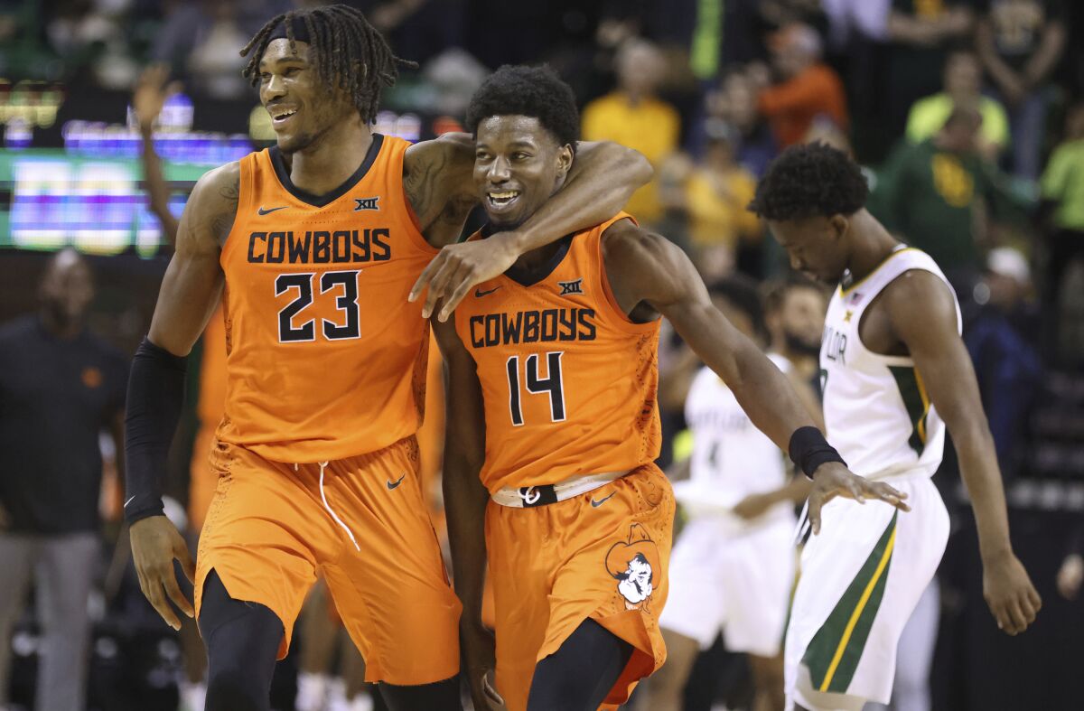 Oklahoma State forward Tyreek Smith, left, walks off with teammate guard Bryce Williams following their win over No. 1 Baylor in an NCAA college basketball game, Saturday, Jan. 15, 2022, in Waco, Texas. Leaving the court for Baylor is Adam Flagler, right. (Rod Aydelotte/Waco Tribune-Herald via AP)