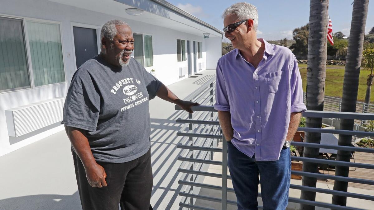 Donald Gates, 77, left, site manager and resident of the Cove Apartments, talks with Larry Haynes, executive director of Mercy House, which helped create the 12-unit community in Newport Beach for homeless veterans and low-income senior citizens.