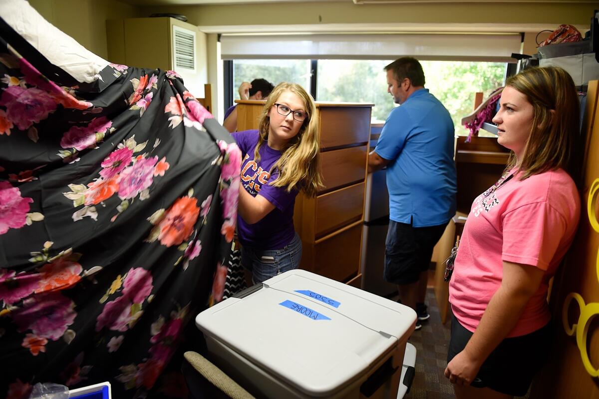 Two young roommates chat while a father helps to rearrange furniture in a dorm room at the University of Evansville's Moore Hall in Evansville, Ind., last month.