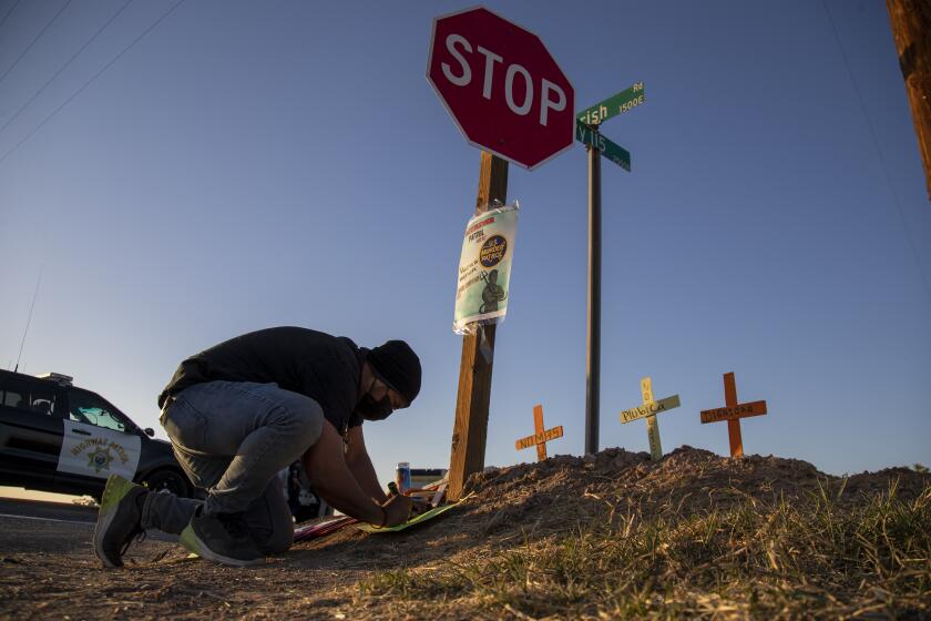 HOLTVILLE, CA - MARCH 2, 2021: Hugo Chavez, an activist with the Coalition for Human Immigration Rights, places crosses at the scene where an SUV carrying 25 people collided with a semi-truck killing 13 on Highway 115 near the Mexican border on March 2, 2021 in Holtville, California. All the back seats had beens stripped form the vehicle. The passengers in the SUV ranged in age form 15-53.(Gina Ferazzi / Los Angeles Times)