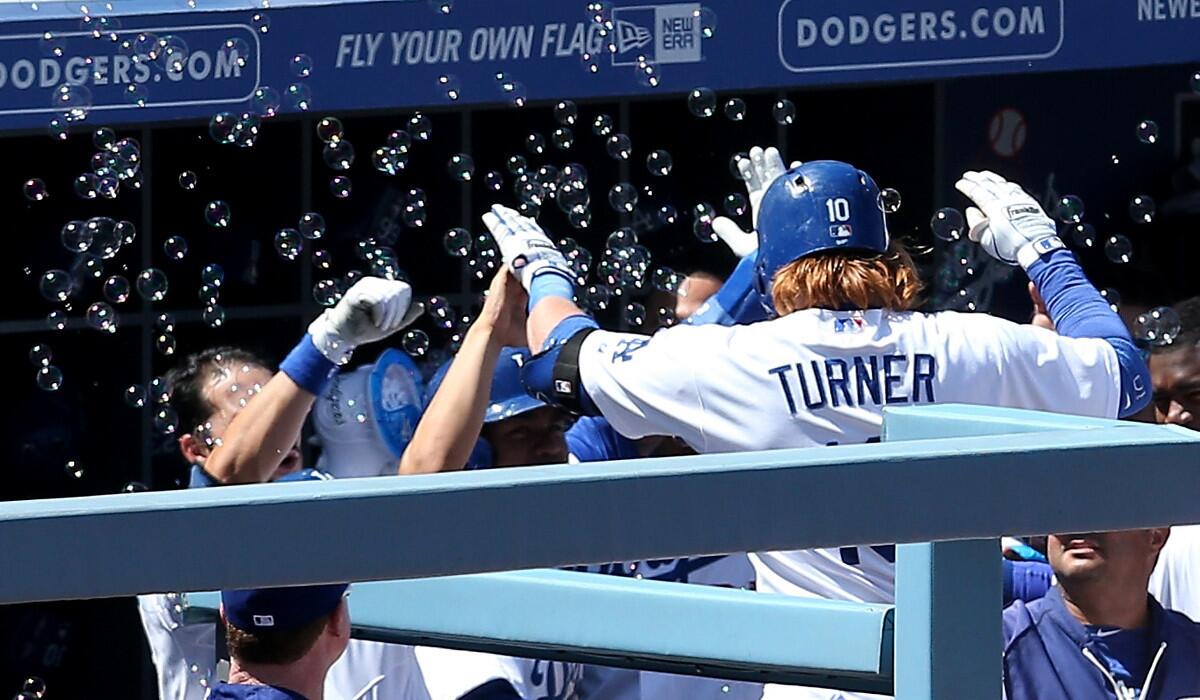 Dodgers teammates greet Justin Turner #10 with high-fives and a flurry of bubbles after he hit a home run against the Nationals last month at Dodger Stadium.