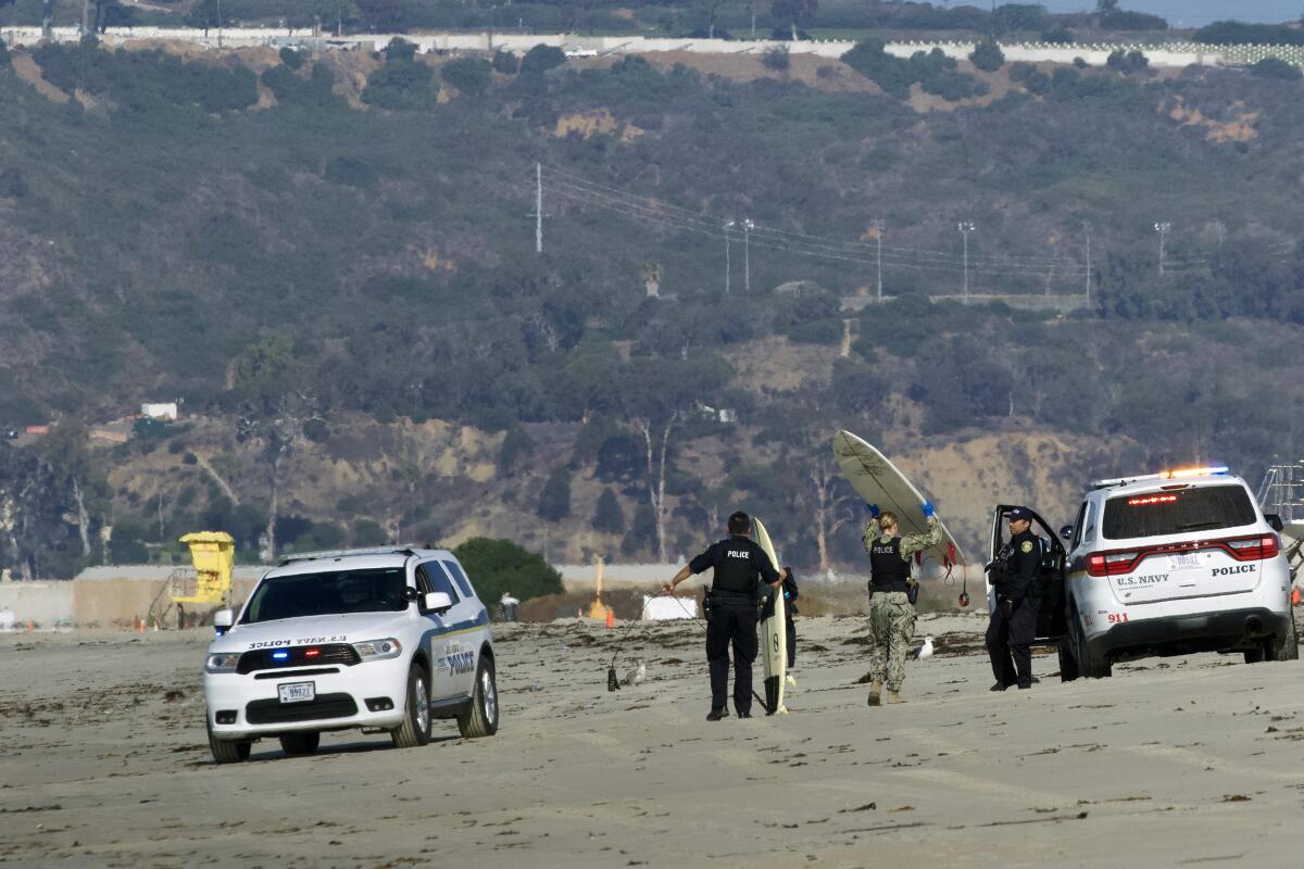 Military police at Naval Air Station North Island carry away surfboards after citing surfers.