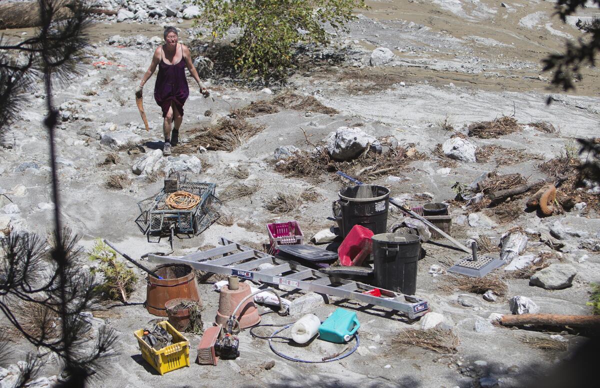 A resident helps pick up Doug Roath's belongings Monday after Sunday's storm sent boulders, mud, water and debris cascading into his yard in Forest Falls.