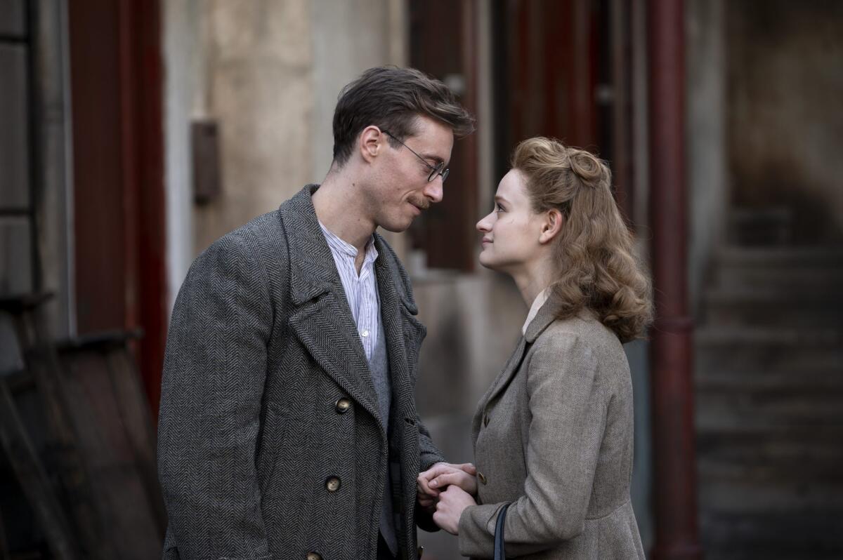 A man and a woman in coats stand face to face.