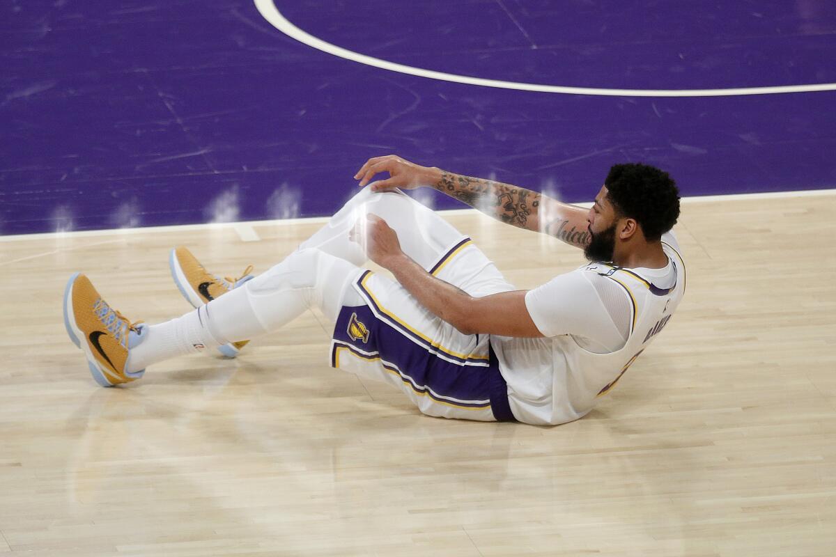 Lakers forward Anthony Davis struggles to get to his feet after injuring his left groin on a driving layup.