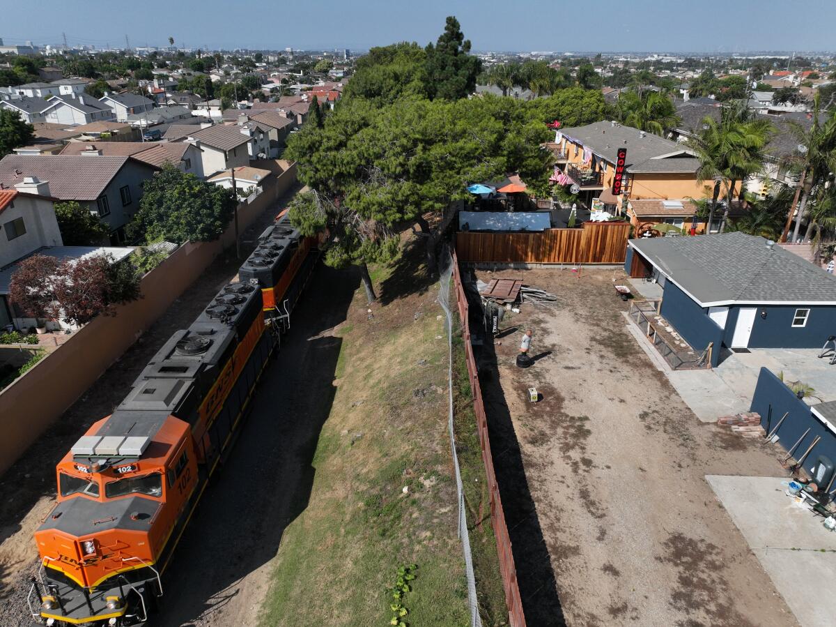 A drone view of a freight train traveling on the tracks next to a home, at right, in Lawndale.