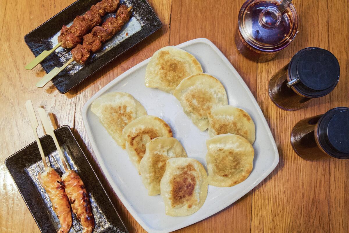 A plate of dumplings and two servings of grilled skewers