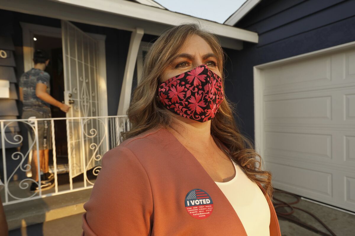 A woman with a face mask and I Voted sticker