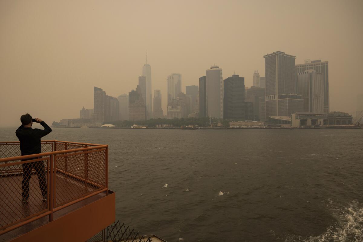 Wildfire smoke blurs the view of New York City's skyline from the Staten Island Ferry.