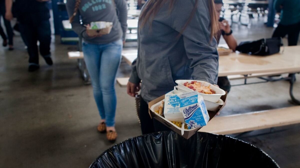 A new law will allow schools to collect unopened food items and untouched fruit for donation to food banks. In this photo from 2014, students from Washington Preparatory High are throwing away unused milk cartons, part of millions of dollars in wasted food.