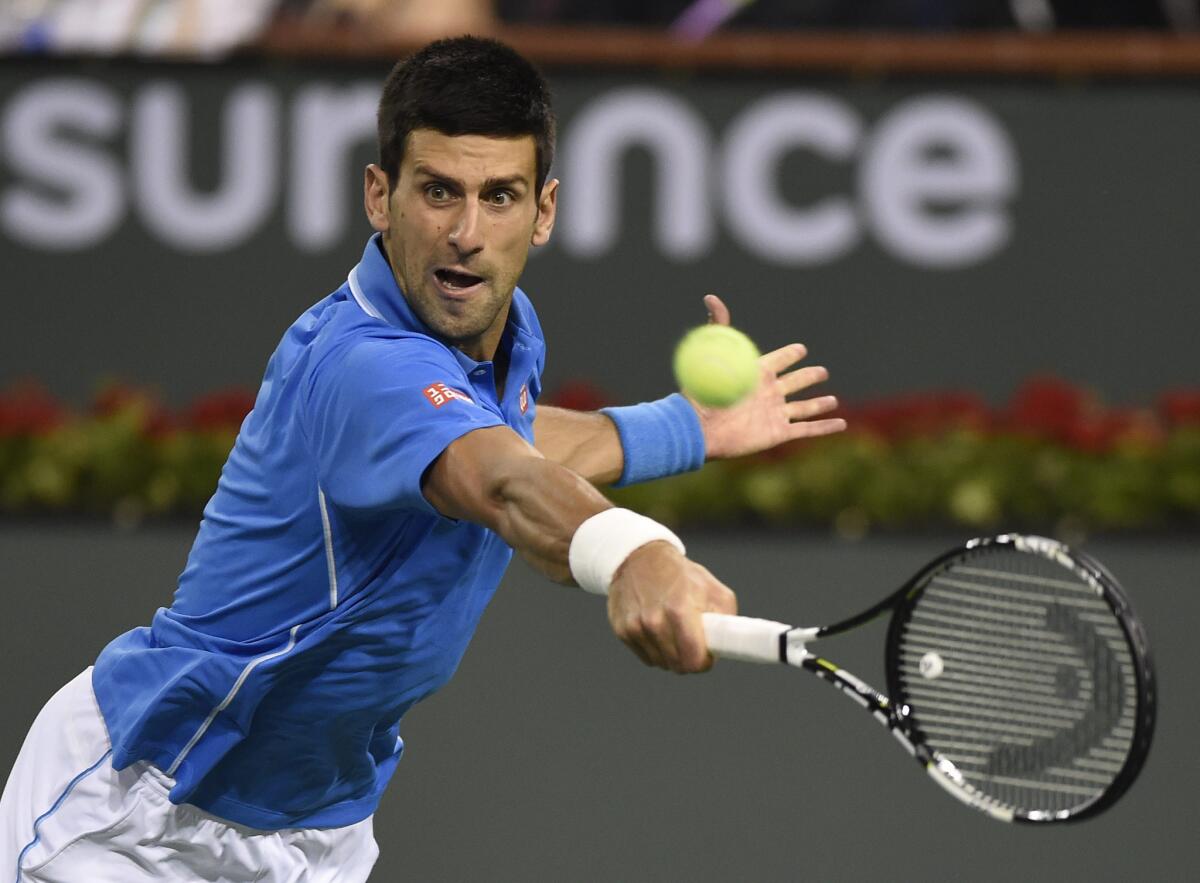 Novak Djokovic reaches to return a shot against John Isner during their match Wednesday night at Indian Wells.