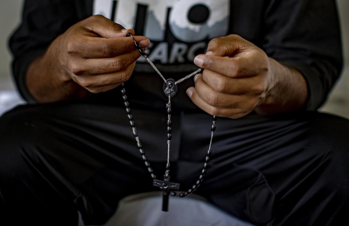 Tsegai, 30, who fled persecution in Eritrea, holds a rosary given to him by family members. 