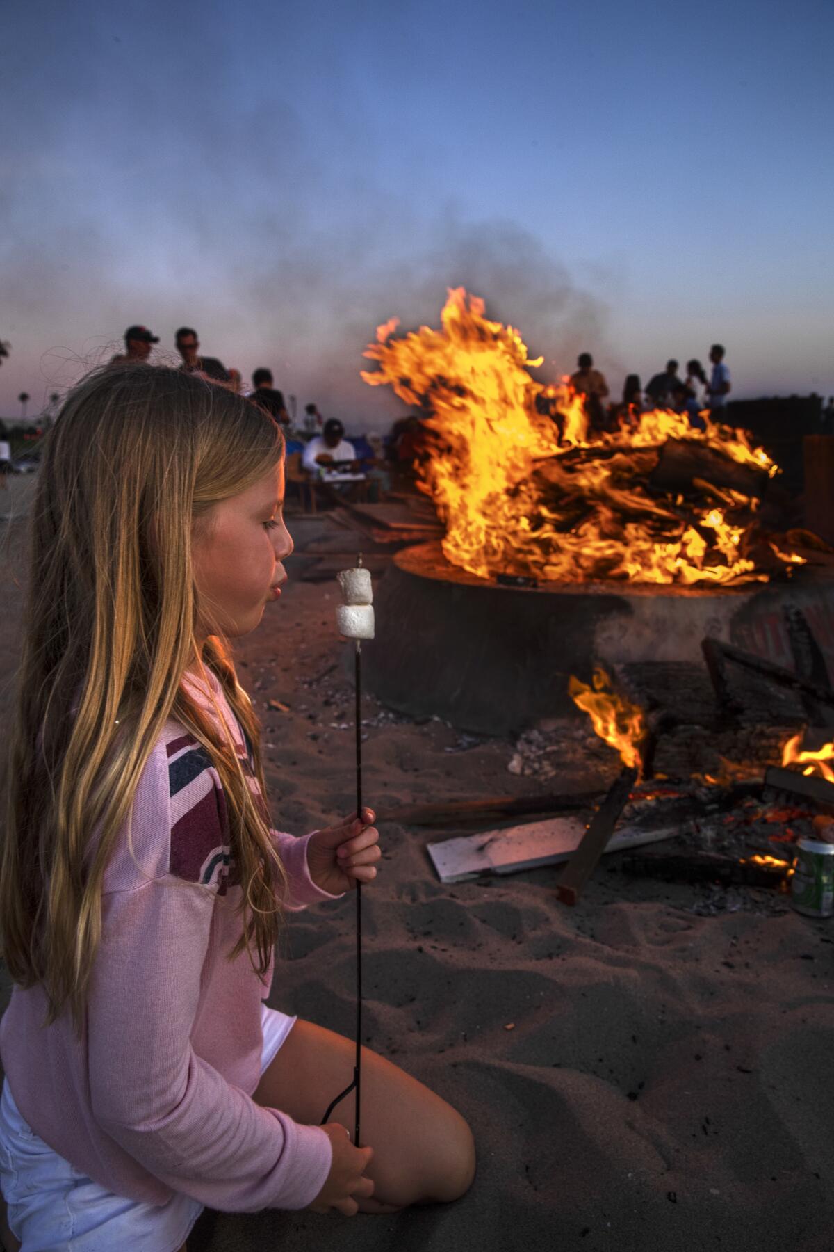 Kate Remillard, 8, of Manhattan Beach, cools her marshmallows at a bonfire at Dockweiler. The beach trends young, but all ages are represented.