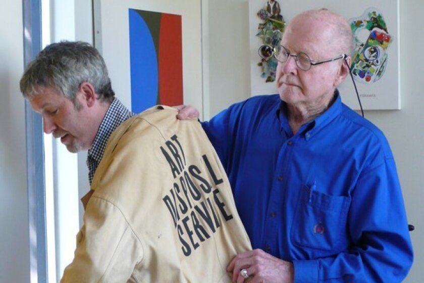 Artist Bob Matheny passes the torch (or at least the uniform) for Art Disposal Service to Dave Hampton. 
