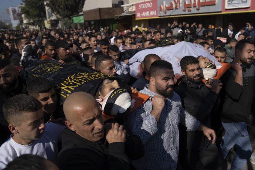 Dolientes palestinos cargan los cuerpos de Naeem Jamal Zubaidi, de 27 años, a la izquierda, y Mohammad Ayman Saadi, de 26, cubiertos con banderas de Yihad Islámica en la ciudad cisjordana de Yenín, el jueves 1 de diciembre de 2022. (AP Foto/Nasser Nasser)