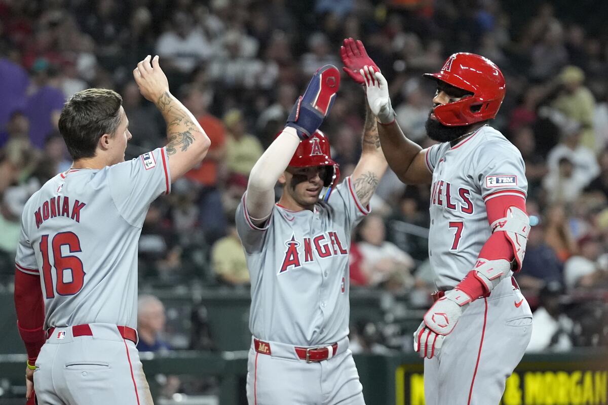 Jo Adell, right, celebrates his three-run home run with Zach Neto, center, and Mickey Moniak.