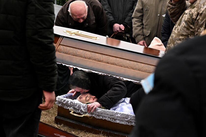 Starychi, Ukraine March 16, 2022: A woman kisses the forehead of a Ukrainian soldier during a funeral Wednesday after being killed at the International Training Center by a Russian missile in Starychi, Ukraine.(Wally Skalij/Los Angeles Times)
