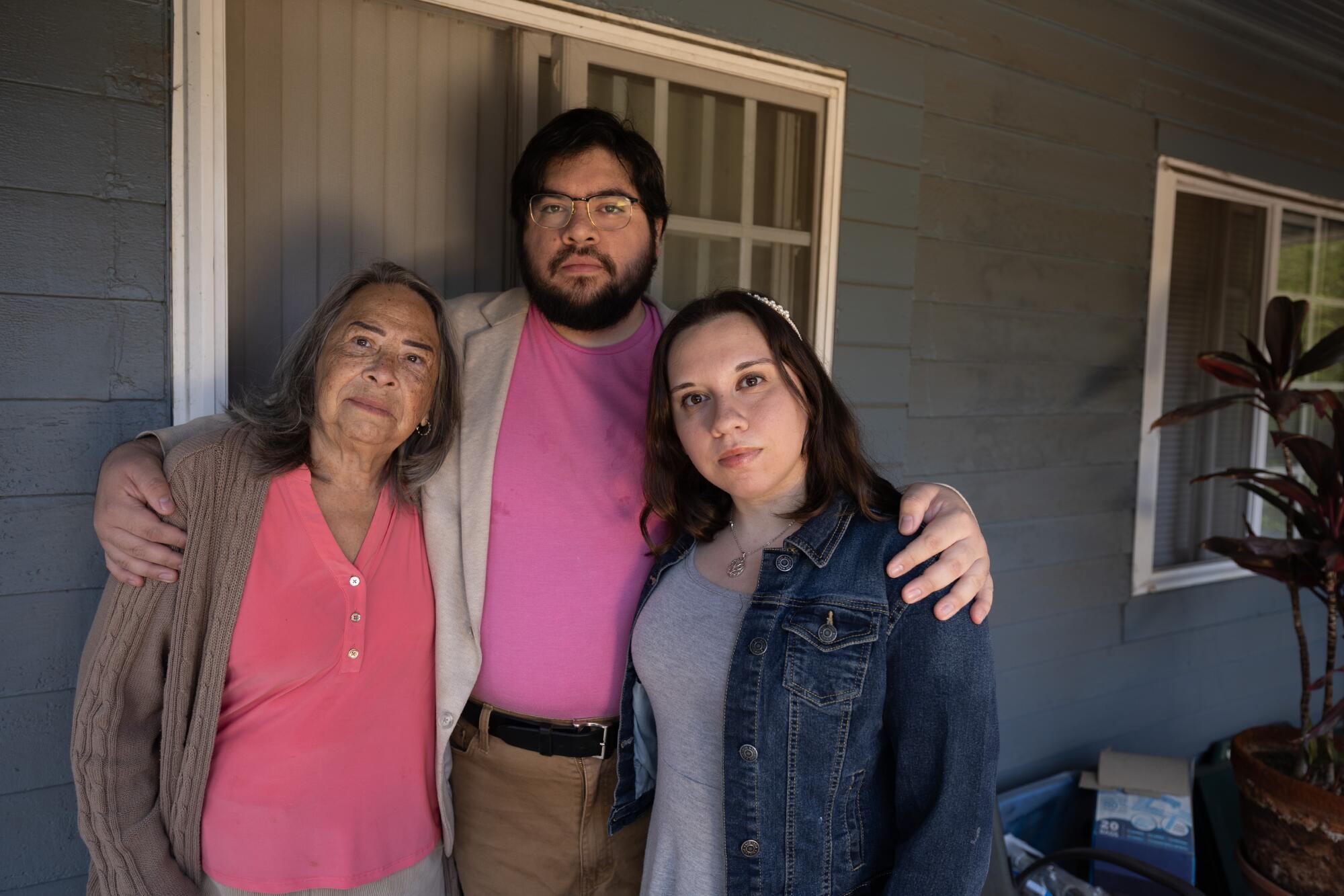 A man with two women outside a house 