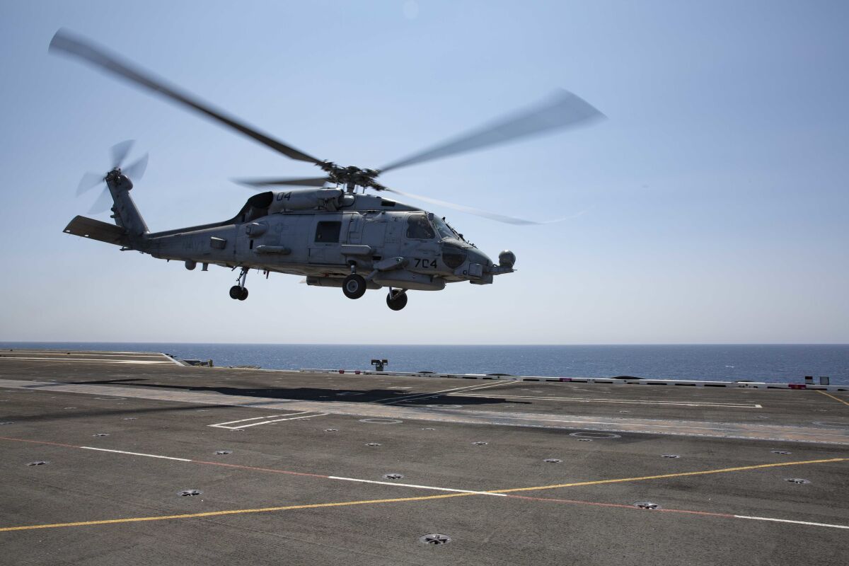 An MH-60R Sea Hawk helicopter takes off of the flight deck of the aircraft carrier USS Abraham Lincoln.