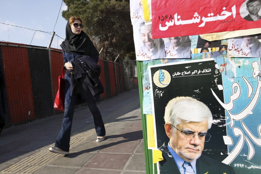 An Iranian woman walks past electoral posters for candidates running in the upcoming parliamentary elections in northern Tehran on Feb. 25.