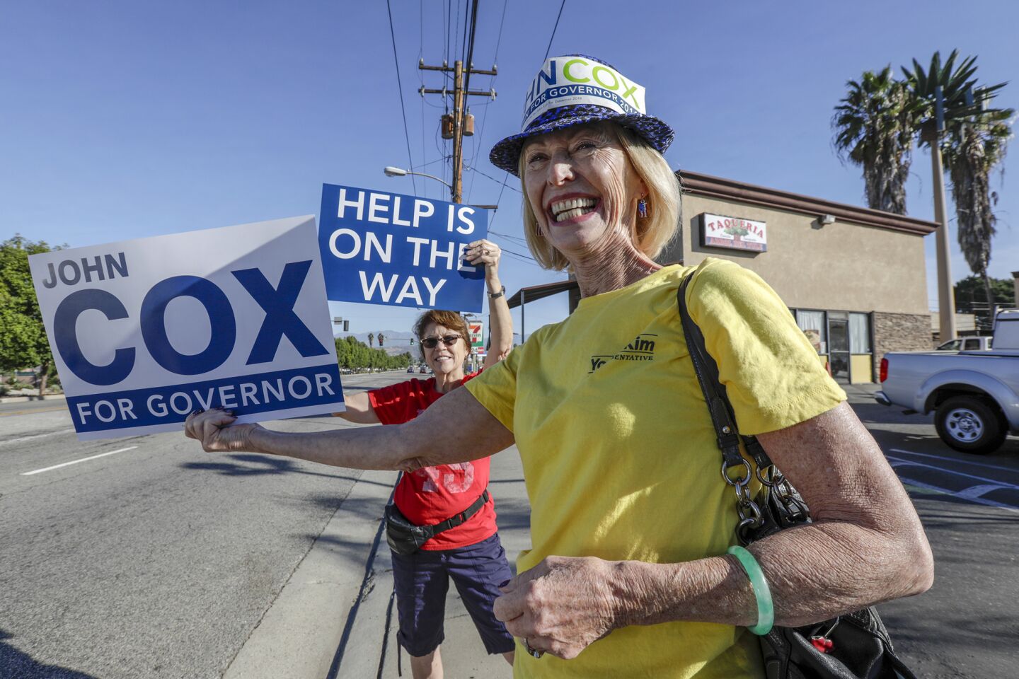 Ione Kauser of La Habra campaigns for gubernatorial candidate John Cox, who stopped in Rowland Heights on his statewide bus tour for a rally with congressional candidate Young Kim.