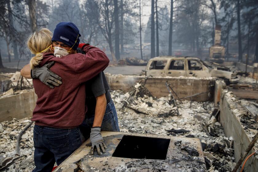 PARADISE, CALIF. -- THURSDAY, NOVEMBER 15, 2018: Michael John Ramirez hugs his wife Charlie Ramirez after they manage to recover her keepsake bracelet that didn't melt in the fire and held a sentimental value as they recover items from their fire safe in the rubble of their destroyed home, after the Camp fire razed through Paradise, Calif., on Nov. 15, 2018. (Marcus Yam / Los Angeles Times)