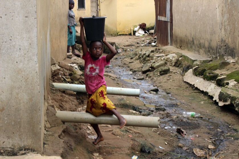 Small girl carrying water in a bucket on her head in Abuja, Nigeria