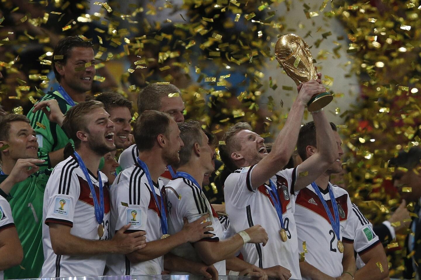 Germany forward Andre Schuerrle, center, holds the trophy as he celebrates with teammates after they beat Argentina for the FIFA World Cup at Maracana Stadium in Rio de Janeiro.